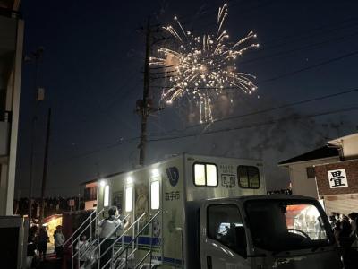 トイレトラックの背後に花火が打ち上げられている