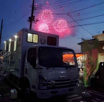 トイレトラックの背後に花火が打ち上げられている