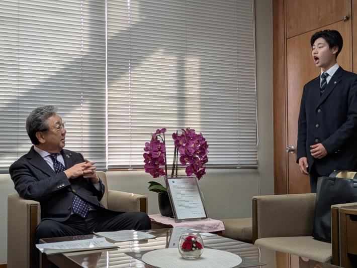 立って歌っている若い男性を見ているもう一人の男性