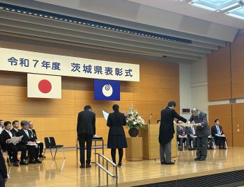 茨城県表彰式と書かれた看板の下で、表彰状の授与が行われている