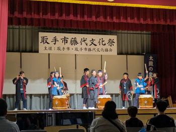 子供と大人複数人が法被姿で和太鼓を演奏している