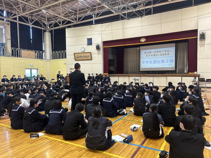 座る生徒たちの中に、マイクを持って立つ生徒が1名いる