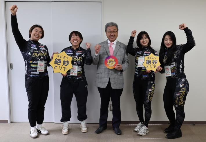 競輪のコスチュームを着た女性とその中央に立つ男性