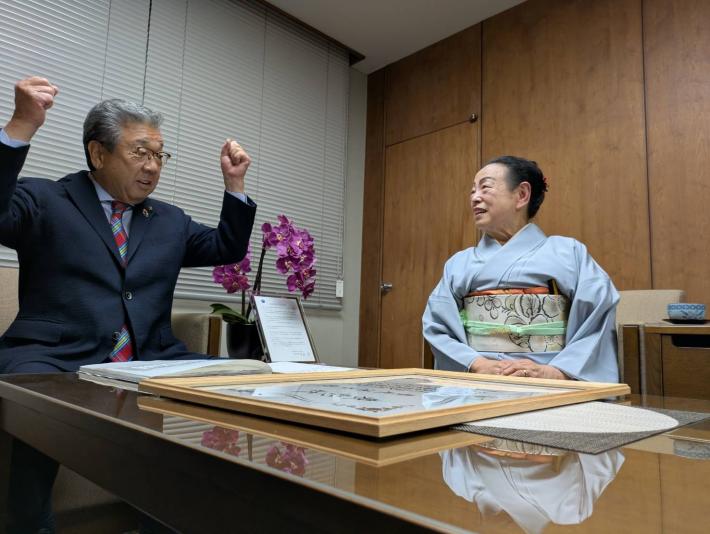 スーツを着た男性と着物を着た女性が応接椅子に座っている。