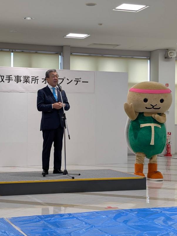 キヤノンオープンデーと書かれた看板の下からあいさつをする男性