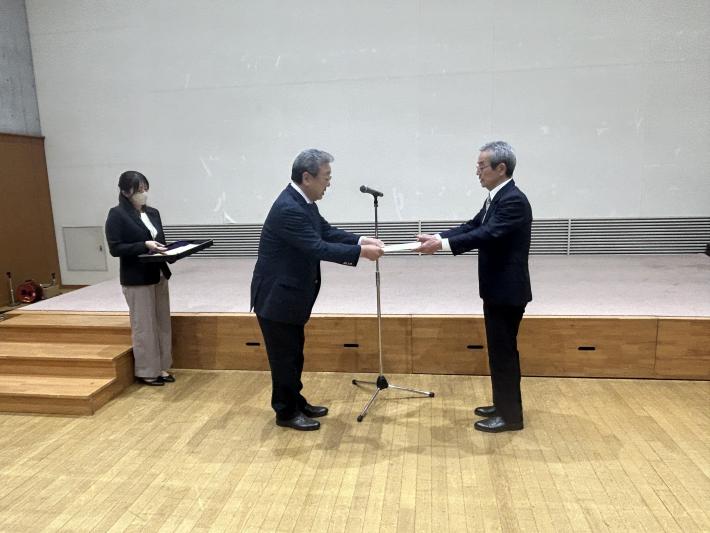 感謝状を贈呈する男性とそれを受け取る男性