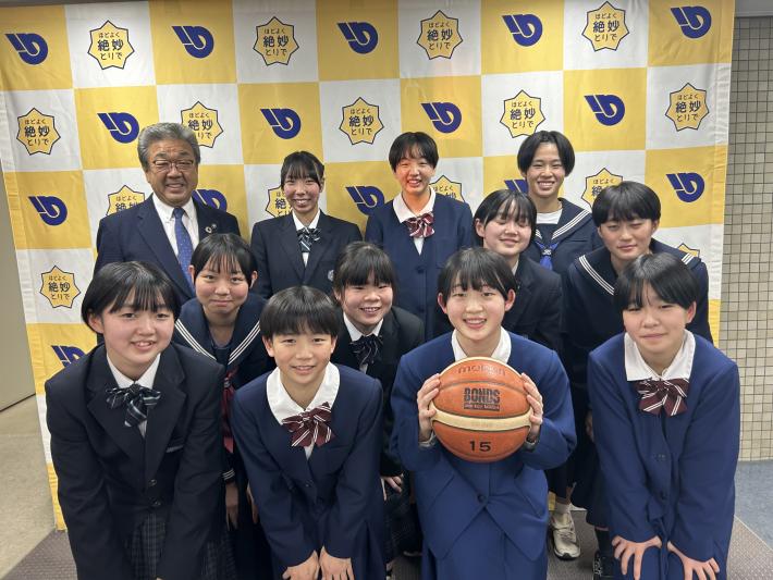 制服を着てパネルの前に立つ女子中学生とスーツを着た男性