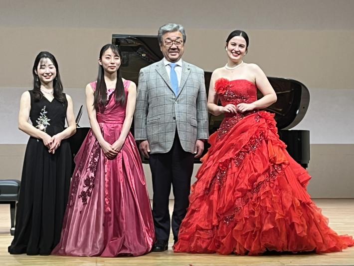 ドレスを着た女性3名に囲まれる男性