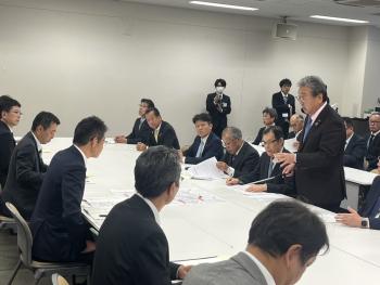 長机の前に立って着座の人たちに説明をする男性