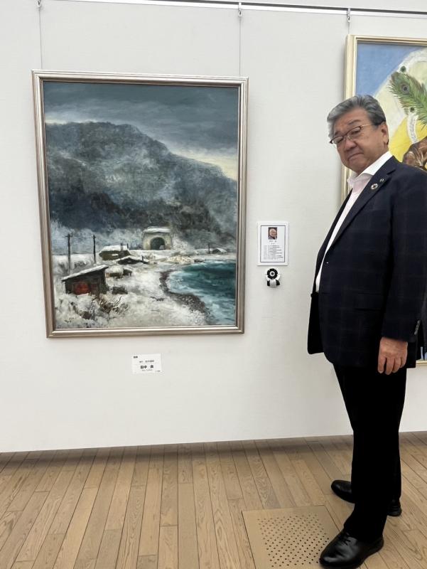 田中先生の絵画の隣に立つ男性