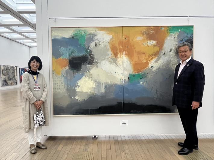 吉金先生の絵画の隣に立つ男性
