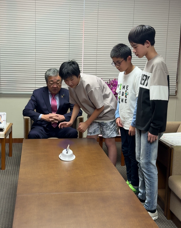 作成したプロペラシューターを走らせる小学生3人と見守る男性