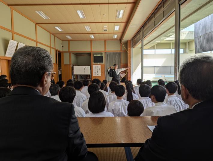 武道場で弓を射る人を見る男性たち