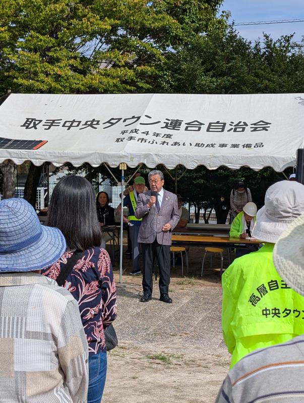 テントの前に立ちあいさつをする男性