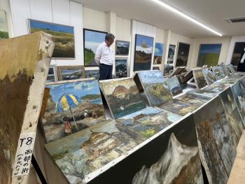 机に並べられた絵画を鑑賞する男性
