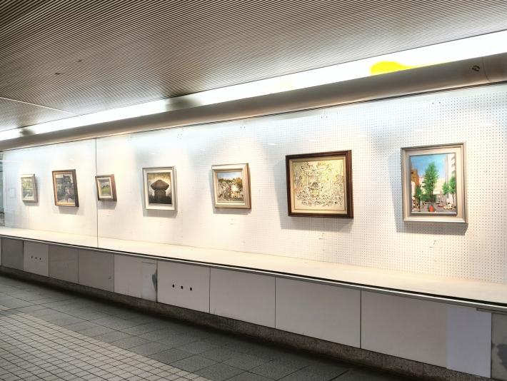 ガラスケース型のギャラリーに複数の絵画作品が飾られている様子