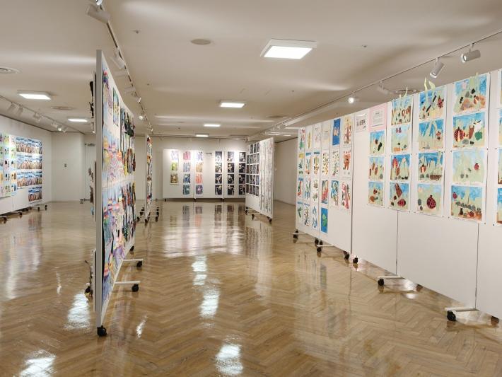 パネルと壁にたくさんの平面作品が飾られている様子