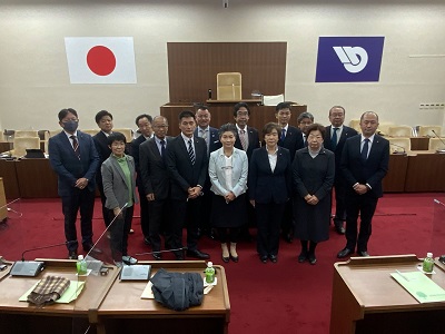 議長席前で2列横隊で並んで記念撮影する15人の視察参加者