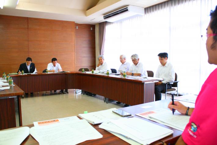 手前に男性職員が、奥のコの字型の座席に四国中央市の議員と職員の計9名が座って、質疑応答をしている。