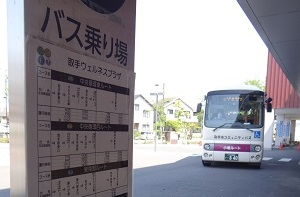 手前にバス停の時刻表が設置されており、その奥にバスが停まっている
