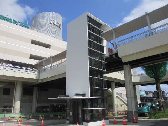 青空の下、取手駅西口のデッキと現在整備中のエレベーターが映っている