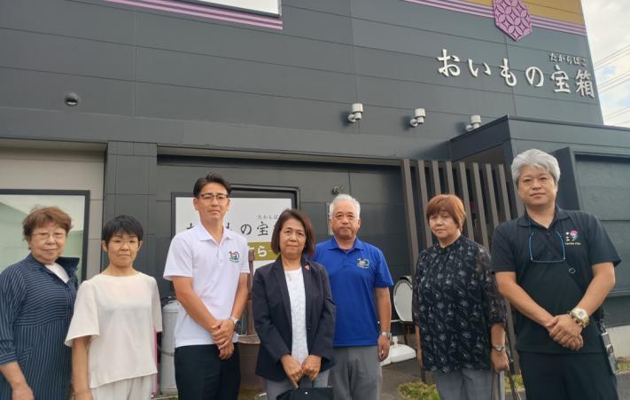 事業所の建物の前に男性と女性の議員数名が並んで立っている