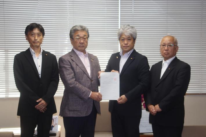 4人の男性が横並びに立って並んでいる