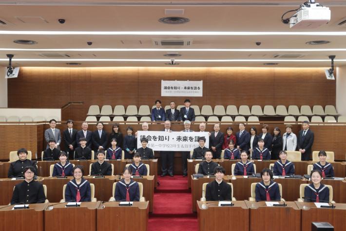 議場に中学生と議員、数十名が並んでいる
