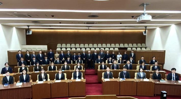 議場に中学生と議員、数十名が並んでいる