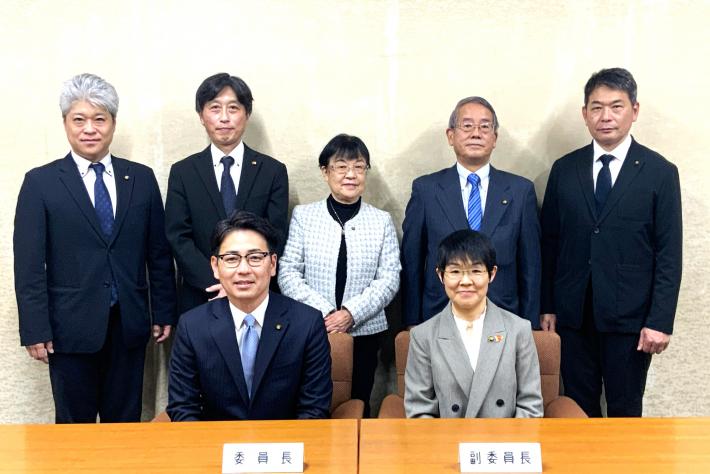 男性と女性の議員が前列は座って、後列は立っている