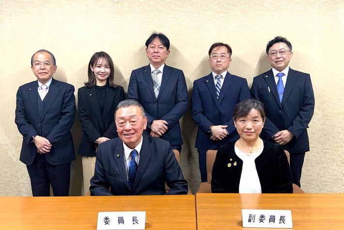 男性と女性の議員が前列は座って、後列は立っている