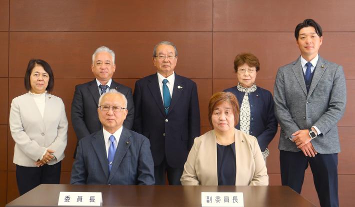 男性と女性の議員が前列は座って、後列は立っている