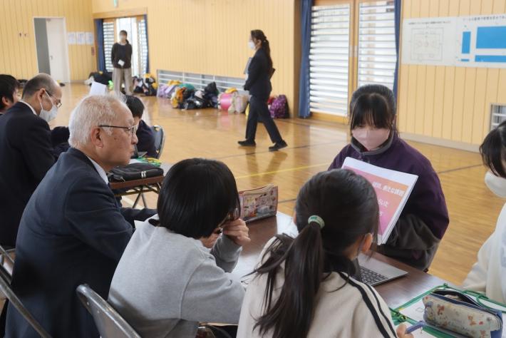小学生が資料を見せながら議員や生徒数名に説明している