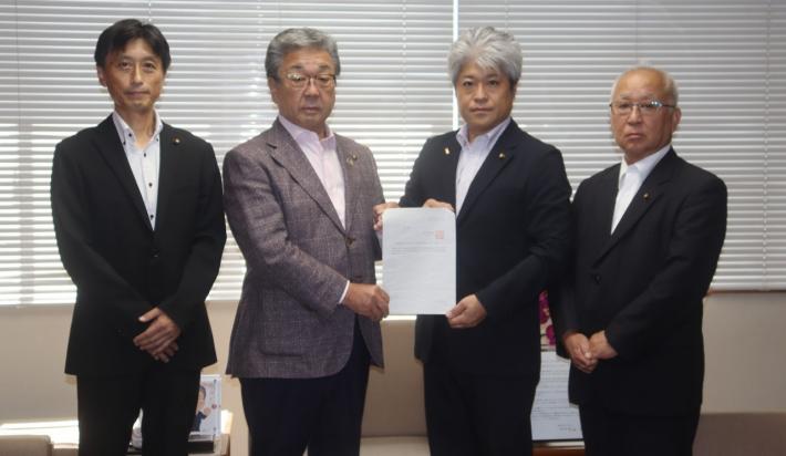 提言書を持って男性4名が立って並んでいる。