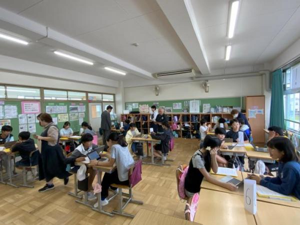 教室内の小学生グループを回ってアドバイスをする市議