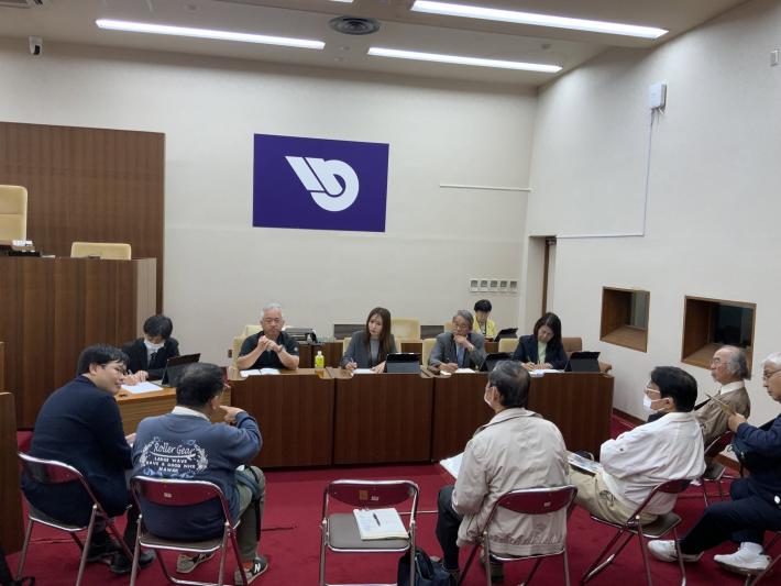 市議会議場で、男女数名の議員と市民数名が椅子に座って話をしている