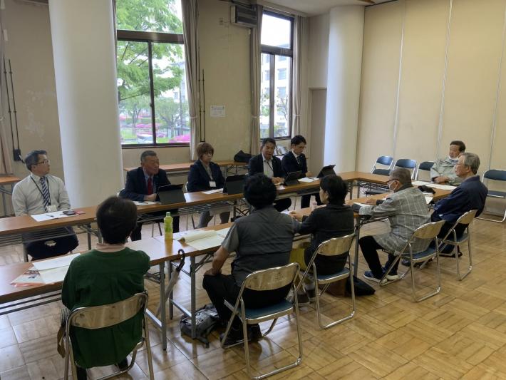 会議室で、男女数名の議員と市民数名が椅子に座って話をしている