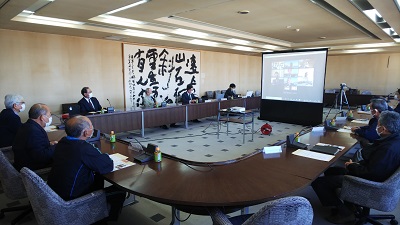 コの字型の座席の中央にはスクリーンが立っている。委員がスクリーンに映り、市民と意見を交換している写真