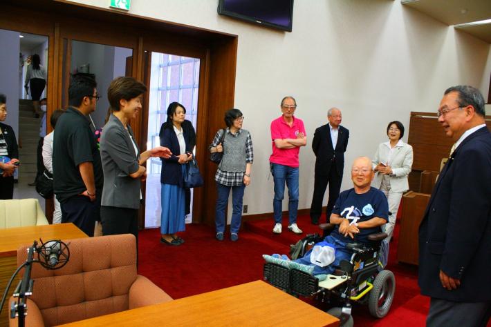 議場内に電動車椅子で入場し、バリアフリーの確認を行う委員ととりで障害者協働ネットワークの皆さん。