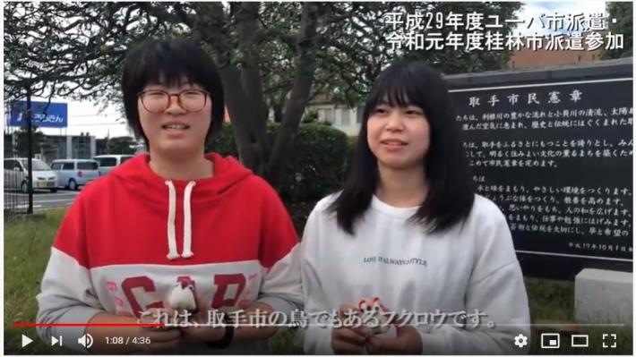 動画の一場面。ユーバ市・桂林市交流事業に参加したことがある2人の女子学生。手にはつるし飾りをもっている
