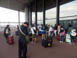 成田空港の出発ロビーに到着し、荷物を移動させる団員達。