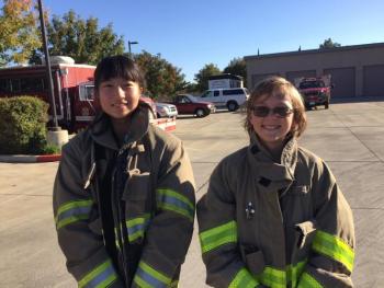 消防服を着た女性の派遣団学生とホストファミリー