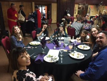 パーティー会場で丸テーブルを囲んで夕食を食べるホストファミリーと学生派遣団員