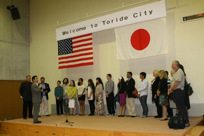 welcome to Toride Cityと書かれた看板の下に立つユーバ市民訪問団