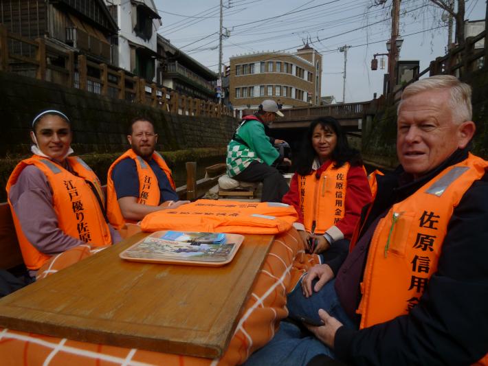 こたつのついている船に乗るユーバ市民訪問団。船に乗っている人はオレンジ色のチョッキを着ている。