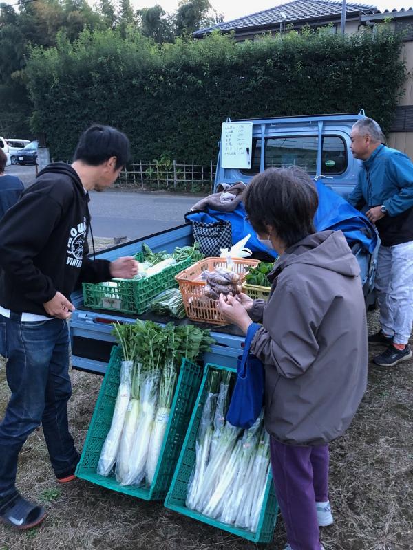 トラックの荷台に置いてある野菜を品定めする男性と女性