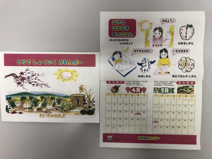 イラストが描かれたカレンダーの表紙とカレンダー見開きのページ。見開きの上部は食育情報、下部はカレンダー。