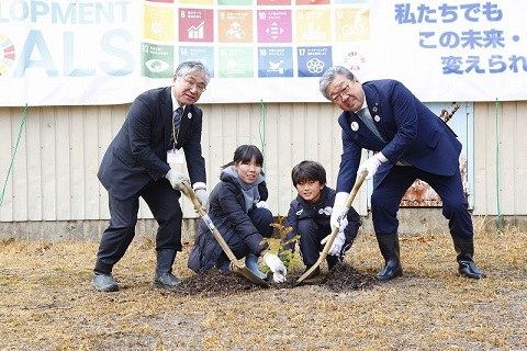 脱炭素チャレンジ広場で植樹記念撮影をしている。左から石塚校長、児童二人、中村市長