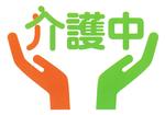介護マーク。オレンジ色の左手と緑色の右手が描かれている。中央上に「介護中」と書かれている