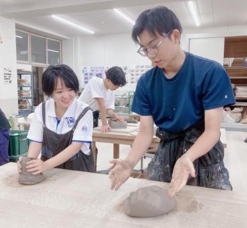 並んで、作業台の上で土をこねる男性と女性の画像。